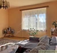 Obývací pokoj v rodinném domě s pohovkou, koberci a hi-fi soupravou.