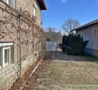 Rodinný dům v Bretce se starou fasádou, vinnou révou a dvorem se stromy.