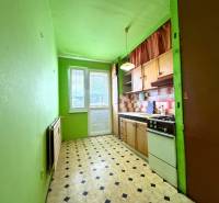 Kuchyně v 2-pokojovém bytě s linkou, zelenými stěnami a černobílou podlahou.