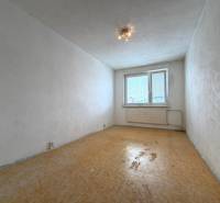 Prázdný pokoj v dvoupokojovém bytě s bílými stěnami a podlahou s dřevěným dekorem.