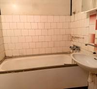 Koupelna v 2-pokojovém bytě s vanou, umyvadlem a staršími stěnovými kachličkami.