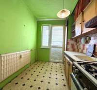 Zelená kuchyně v 2-pokojovém bytě s kachličkami a plynovým sporákem.