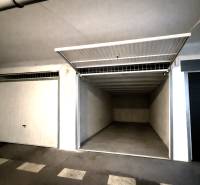 Otevřená garáž s prázdným interiérem a bílými stěnami.