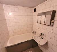 Koupelna s vanou a bílými obklady v 2-pokojovém bytě.