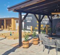 Exteriér v Nové Dedince s gastro prostory, terasou a dětským hřištěm.