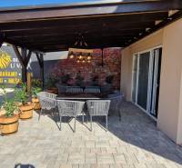 Gastro prostory v Nové Dedince s venkovním posezením a cihlovou zdí.