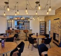 Gastro prostory s podlahou s dřevěným dekorem a závěsnými žárovkami.