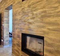 Interiér gastro prostorů s krbem a podlahou s dřevěným dekorem.