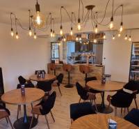 Interiér gastro prostorů s podlahou s dřevěným dekorem a osvětlením žárovkami.