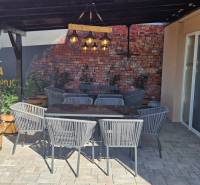 V exteriérových gastro prostorech v Nové Dedince jsou ratanové židle a cihlová zeď.