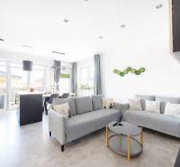 Obývací pokoj ve 3-pokojovém bytě s podlahou s dřevěným dekorem a šedými sedačkami.