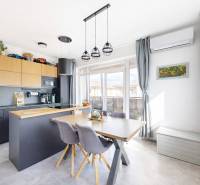 Kuchyně ve 3-pokojovém bytě s podlahou s dřevěným dekorem, jídelním stolem a moderní klimatizací.