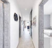 Chodba v 3-pokojovém bytě s bílými stěnami, šedými dveřmi a světlou podlahou.