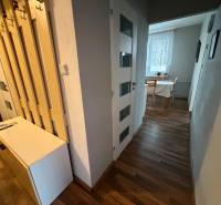 Chodba v 3-pokojovém bytě s podlahou s dřevěným dekorem a stolem u okna.