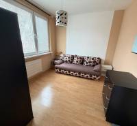 Pokoj s pohovkou, komodou a podlahou s dřevěným dekorem v 3-pokojovém bytě.