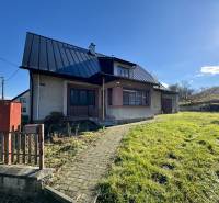 Rodinný dům v Šarišském Černém s trávníkem, šikmou střechou a zahradou.