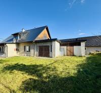 Rodinný dům v Šarišském Černém s trávníkem, moderní střechou a částečně dřevěnými stěnami.