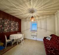 Interiér rodinného domu s dřevěným obkladem a květinovým obrazem na stěně.