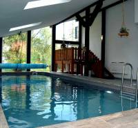 Interiér rekreačního apartmánu s podlahou s dřevěným dekorem a krytým bazénem.