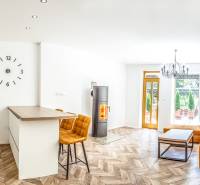 Světlý rekreační apartmán s kuchyní, oranžovou sedačkou a podlahou s dřevěným dekorem.