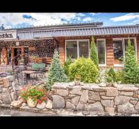 Kamenná fasáda Rekreačního apartmánu ve Štrbě s terasou a květinovou výzdobou.