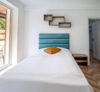 Jednolůžková postel v rekreačním apartmánu s podlahou s dřevěným dekorem a velkým oknem.