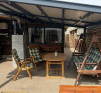 Zahradní posezení s dřevěnými křesly, houpačkou a květináči u 2pokojového bytu.