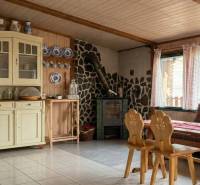 Vidět útulnou místnost s kamny, dřevěným obložením a nábytkem v 2-pokojovém bytě.