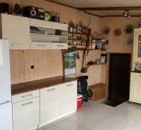 Kuchyně v 2-pokojovém bytě se světlým nábytkem, bílou lednicí a dekoracemi na stěně.