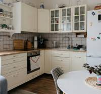 Kuchyně v 2-pokojovém bytě s bílým nábytkem a podlahou s dřevěným dekorem.