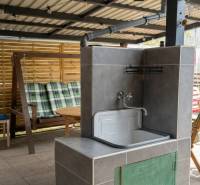 Zastřešená terasa na Coburgově ulici v Trnavě, s umyvadlem, houpačkou a dětským stolkem.