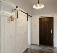 Chodba s šedou podlahou a bílými posuvnými dveřmi v 2pokojovém bytě.