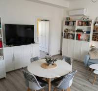 Obývací pokoj v 2pokojovém bytě s podlahou s dřevěným dekorem, gaučem a televizí.