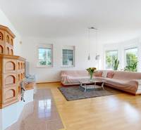 Obývací pokoj v rodinném domě s kamny, pohovkou a podlahou s dřevěným dekorem.