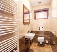 Koupelna v rodinném domě s podlahou s dřevěným dekorem, umyvadlem a topným tělesem.