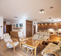 Interiér rodinného domu s prostorným obývacím pokojem, kuchyňskou linkou a podlahou s dřevěným dekorem.