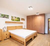 Ložnice v rodinném domě s postelí, skříněmi a podlahou s dřevěným dekorem.