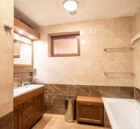 Koupelna v rodinném domě s vanou, umyvadlem, sprchovým koutem a podlahou s dřevěným dekorem.