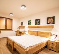 Ložnice v rodinném domě s podlahou s dřevěným dekorem, obrazy a pracovními stoly.