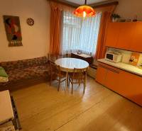 Interiér rodinného domu s retro kuchyní, kulatým stolem a pohovkou.