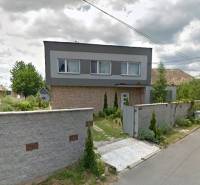 Rodinný dům v Bystričce s upravenou zahradou a vysokým plotem podél ulice.