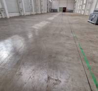 Prostorný interiér skladů a hal s betonovou podlahou a balíky na levé straně.