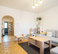 Obývací pokoj v 3-pokojovém bytě s podlahou s dřevěným dekorem a světlým nábytkem.