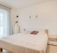 Světlá ložnice v 3-pokojovém bytě s bílým nábytkem a postelí.