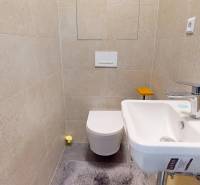 Kompaktní koupelna se světlými dlaždicemi, umyvadlem a toaletou ve 3-pokojovém bytě.