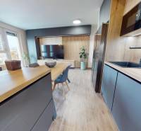 Kuchyně ve 3-pokojovém bytě s podlahou s dřevěným dekorem a jídelním stolem.