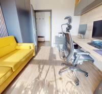Pracovna v 3-pokojovém bytě s podlahou s dřevěným dekorem a žlutou pohovkou.