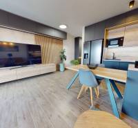 Obývací pokoj v 3-pokojovém bytě s podlahou s dřevěným dekorem a kuchyní.