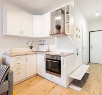 Kuchyně s bílými skříňkami v 1-pokojovém bytě a podlahou s dřevěným dekorem.