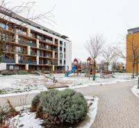 Bytový dům na Béžové ulici v Bratislavě - Petržalce s dětským hřištěm a zimní atmosférou.